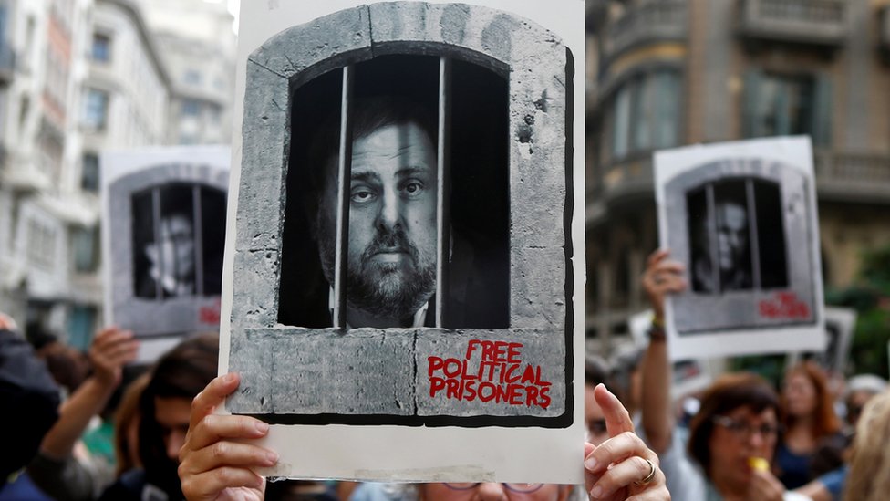 A protester shows a photo of Catalan former vice-president Oriol Junqueras behind bars as hundreds of people block the central Via Laietana in Barcelona, Spain, 14 October 2019