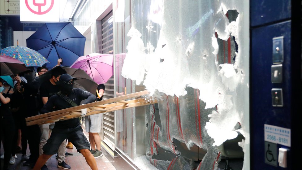 Мужчина разбивает лестницей окно отделения Bank of China в Гонконге