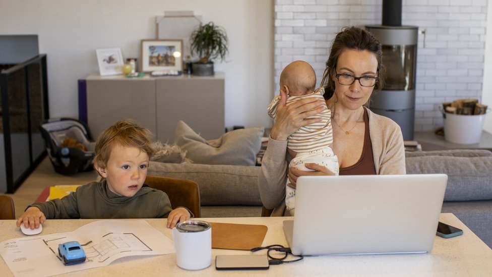 Woman working from home, with her two young children around her