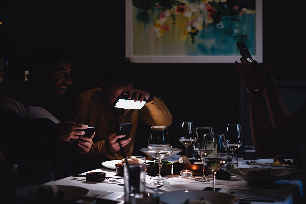رجلان يلتقطان صورا لطعامهما في أحد المطاعم