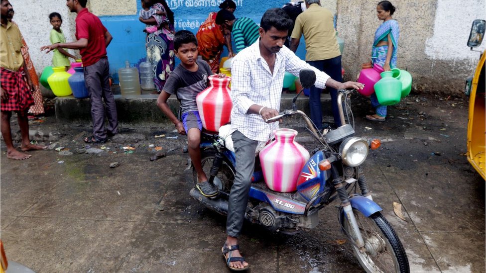 Индийский мужчина с ребенком расставляет пластиковые сосуды с питьевой водой на своем скутере в пункте распределения воды, который пополняется цистернами с водой, в Ченнаи, столице южного индийского штата Тамил Наду, среда, 20 июня 2019 г. || |