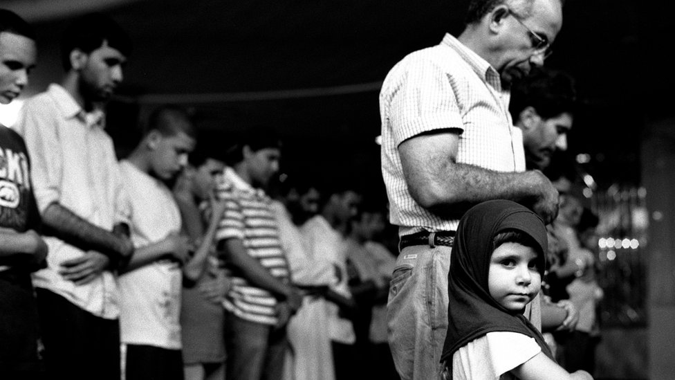 Chica joven en oraciones con su padre, en la Sociedad Musulmana Americana, Brooklyn, 2010. Chica joven en oraciones con su padre, en la Sociedad Musulmana Americana, Brooklyn, 2010.