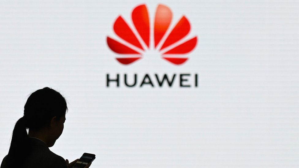 Женщина перед логотипом Huawei