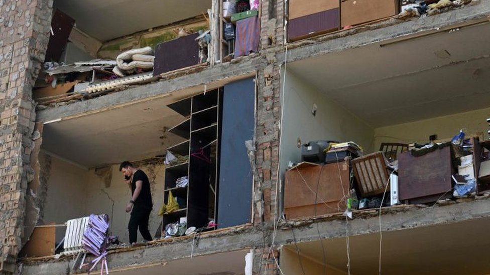 Rusya saldırılarında evinin duvarı yıkılan bir kişinin cep telefonuyla konuştuğu görülüyor.