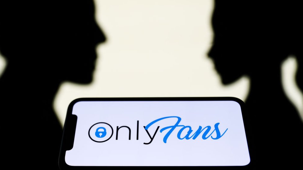 Celular con el logo de OnlyFans y dos perfiles de fondo