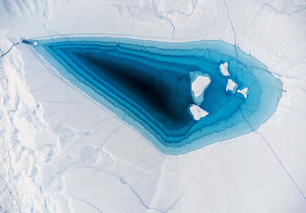 ماء بلون الفيروزفي قمة جبل جليدي في غرينلاند . تشكلت في الجبل الجليدي لاكوبشافن حيث يجرف الجليد قبل أن يننتهي به المطاف في المحيط الأطلسي الشمالي.