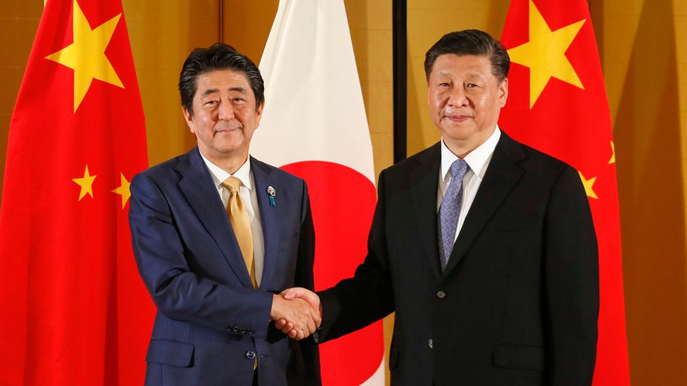 Премьер-министр Японии Синдзо Абэ (справа) пожимает руку президенту Китая Си Цзиньпину