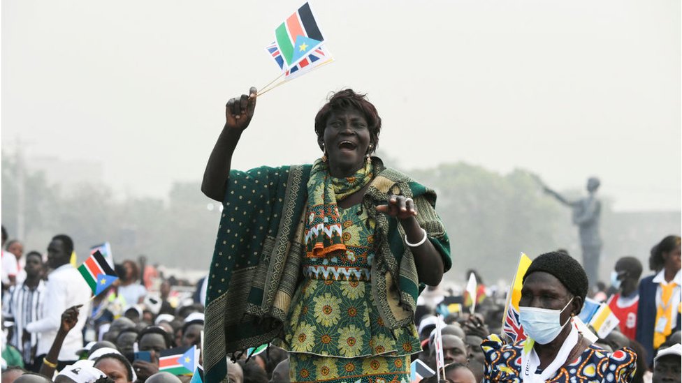 امرأة تحمل علم جنوب السودان وتهتف وسط حشد من الناس