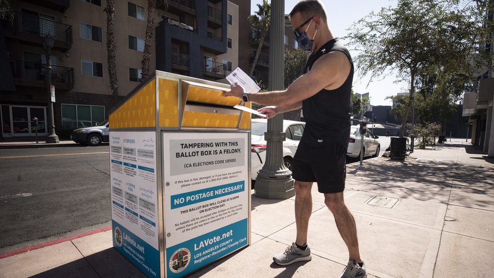 Un hombre deposita un voto en un buzón en la calle