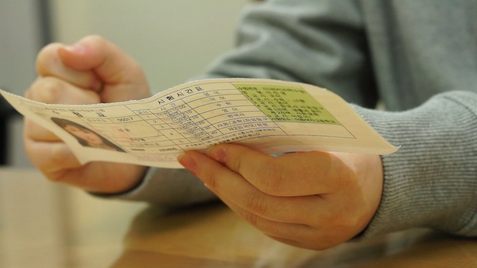Jin-yeong sostiene la vieja tarjeta de asistencia al examen