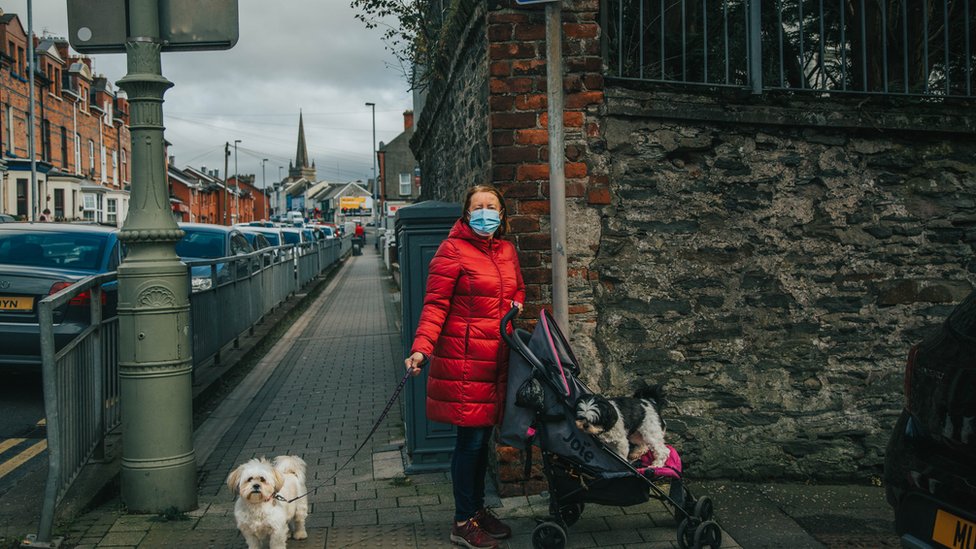 Женщина со своими собаками идет по улице