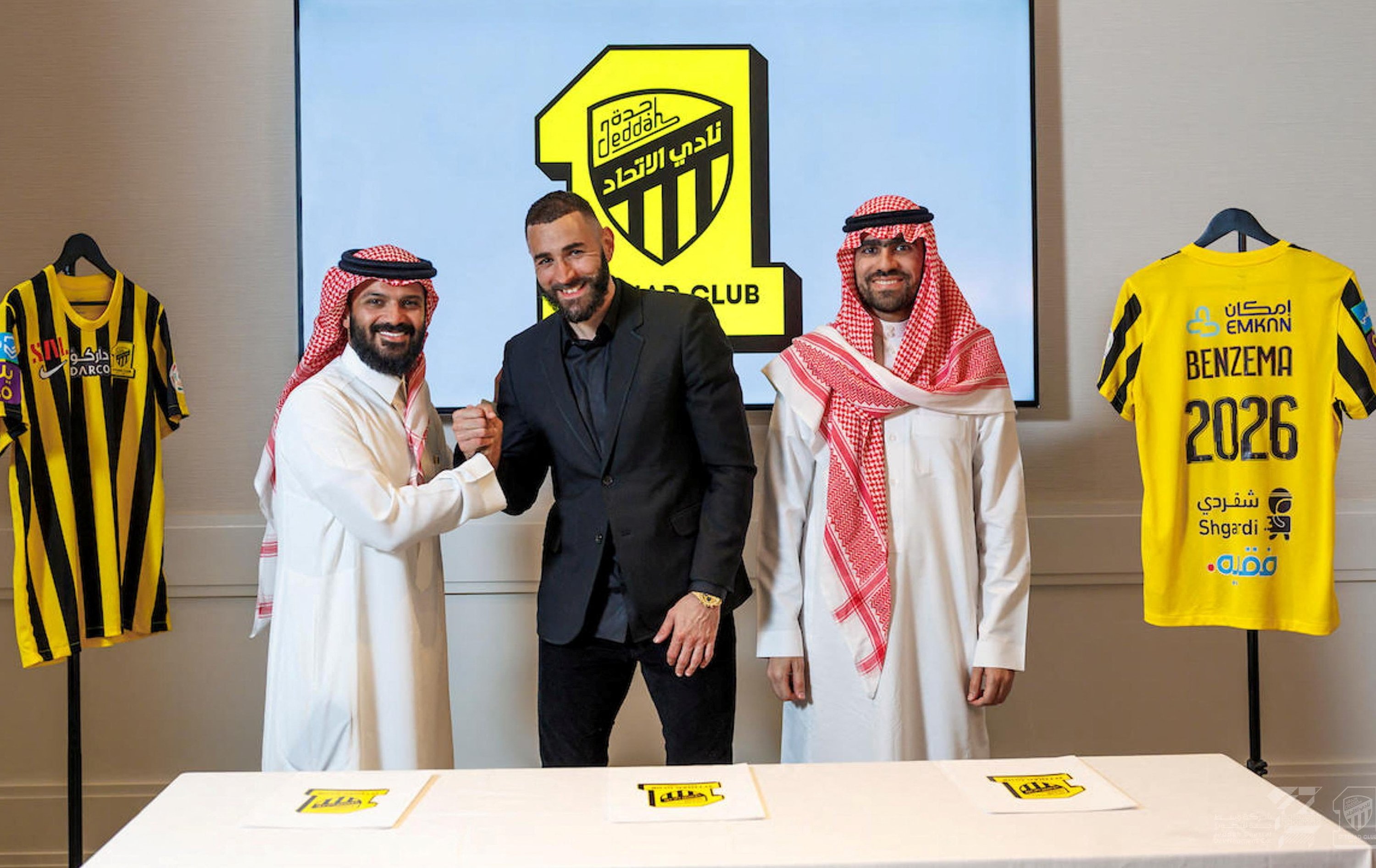 كريم بنزيمة يقف مع أعضاء فريق الاتحاد السعودي لكرة القدم بعد توقيع عقده مع النادي