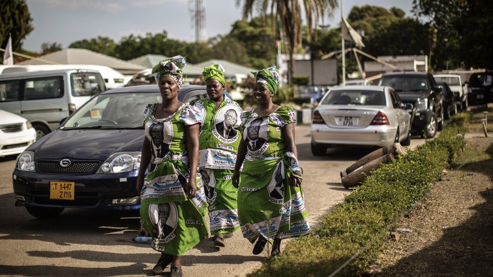 Женщины в платьях с портретом покойного президента Замбии Майкла Саты прибывают на поминальную службу в Лусаке, Замбия, 10 ноября 2014 года, накануне государственных похорон Саты