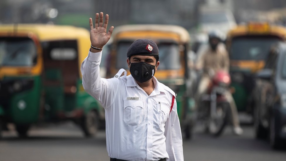 Дорожный полицейский носит маску, чтобы защитить себя от загрязнения воздуха на перекрестке во время ограничений на использование частных транспортных средств по номерным знакам, туманным утром в Нью-Дели, Индия, 4 ноября 2019 года.