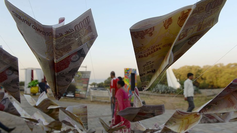 Люди проходят мимо репродукций демонизированных банкнот в 500 и 1000 рупий в рамках выставки уличного искусства в Мумбаи