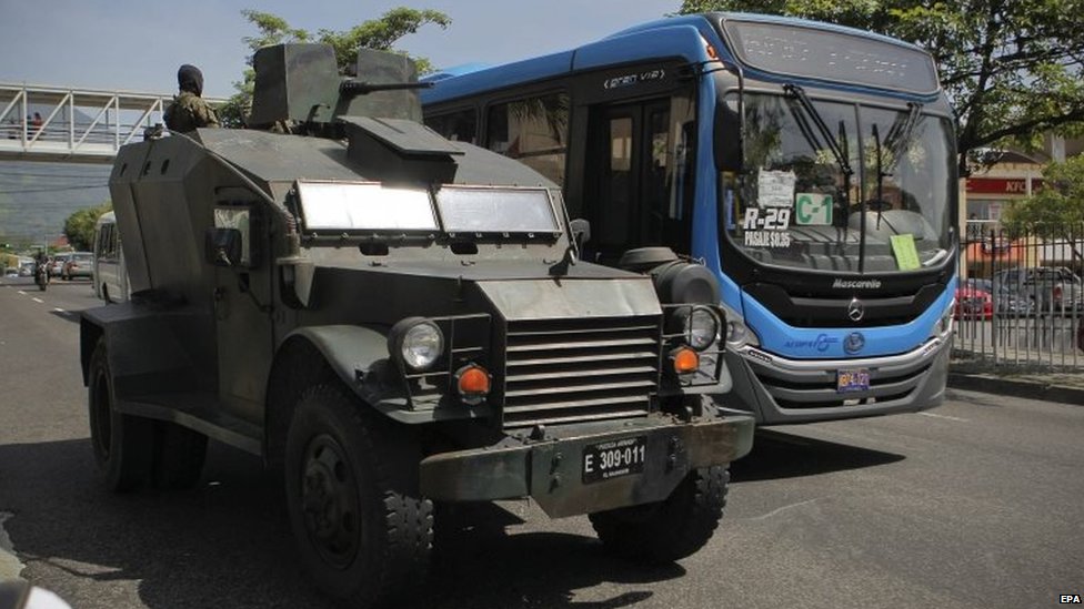 Автомобиль Сальвадорской армии патрулирует улицу рядом с общественным автобусом в Сан-Сальвадоре 29 июля 2015 года.