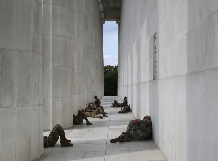 Члены Национальной гвардии отдыхают от жары у Мемориала Линкольна, в то время как протестующие проводят демонстрацию против жестокости и расизма со стороны полиции 6 июня 2020 года в Вашингтоне, округ Колумбия