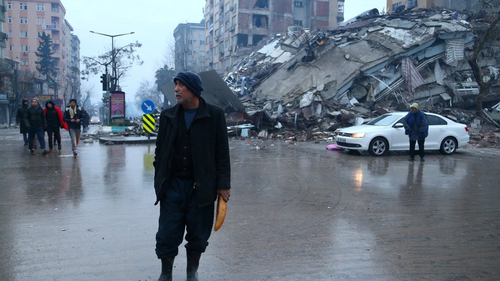 A man holding bread walks in a street after an earthquake in Kahramanmaras, Turkey, 6 February 2023