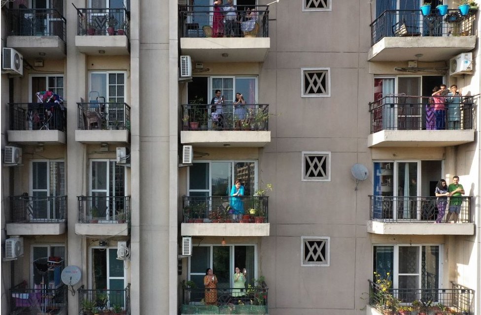 Люди собираются на балконах жилого дома в Газиабаде, Индия
