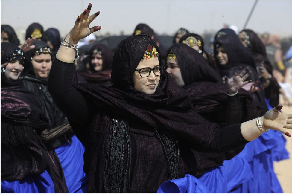 نساء صحراويات يرتدين الحجاب الأسود مع ما يبدو أنه أغلفة زرقاء.