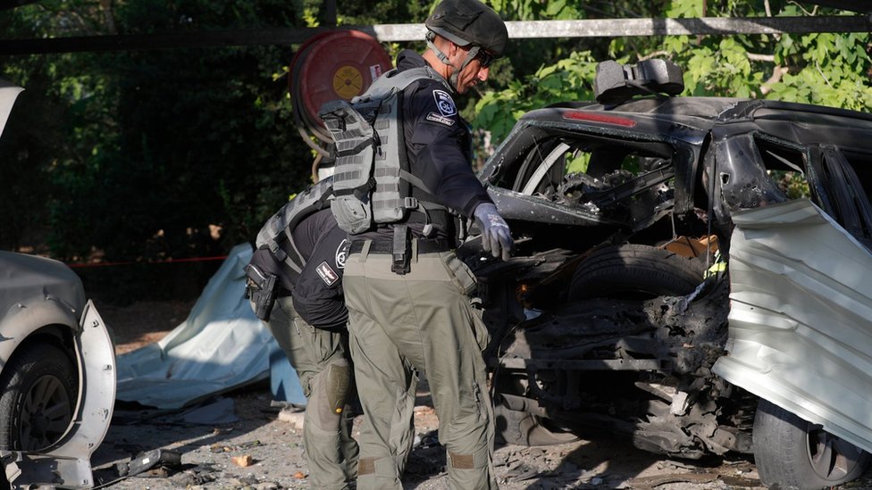 Un policía israelí ante un auto impactado por un cohete palestino