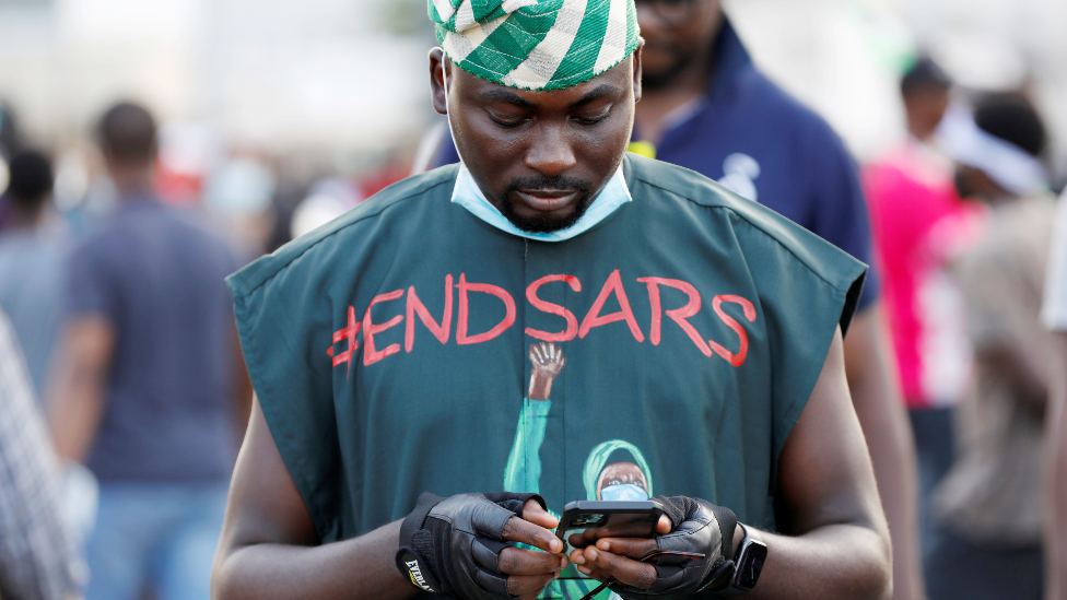 An #EndSars protester in a T-shirt with the hashtag against police brutality using his phone in Lagos, Nigeria - October 2020