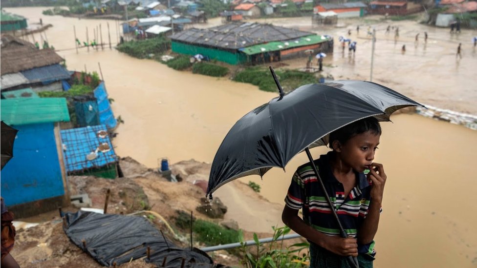 Мальчик с зонтиком перед затопленной деревней