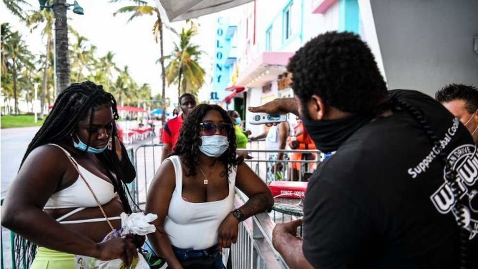 Охранник проверяет температуру у женщины у входа в ресторан на Оушен Драйв в Майами-Бич, Флорида, 24 июня 2020 года