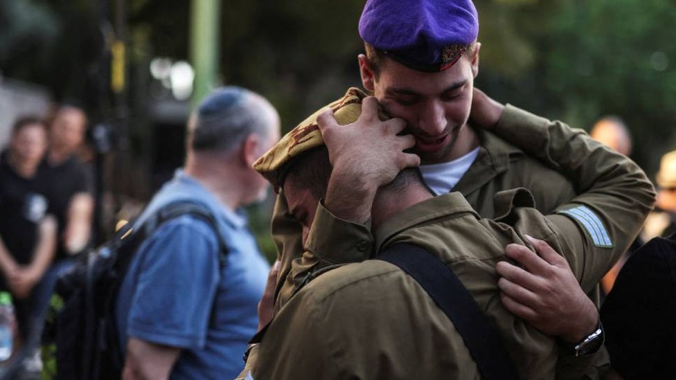 Israeli soldiers embrace as they mourn a fellow soldier