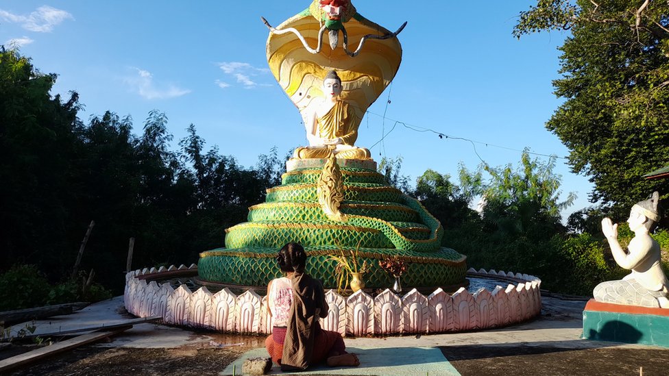 Yin Yin Myint berlutut di depan pagoda.