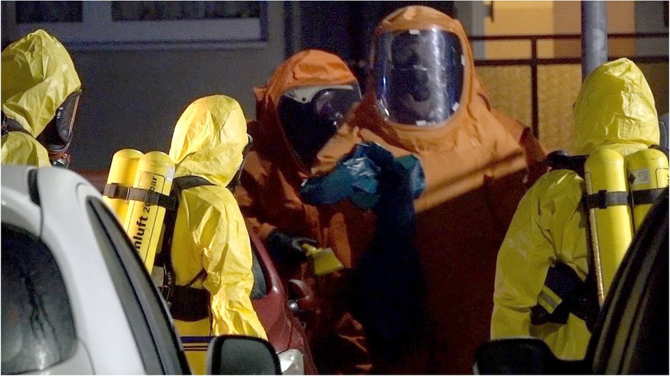 Firefighters wear protective suits during an investigation for poisonous substances at a house near the place where a courier driver was found dead inside his van in Haldensleben