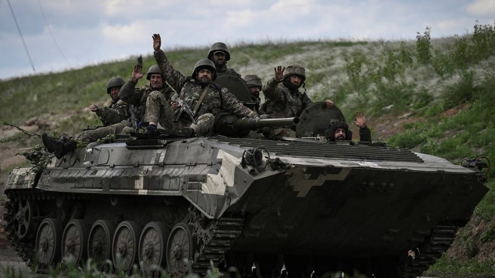 يلوح الجنود الأوكرانيون أثناء تحركهم نحو نقطة تفتيش بالقرب من مدينة ليسيتشانسك في المنطقة الشرقية من دونباس في 23 مايو