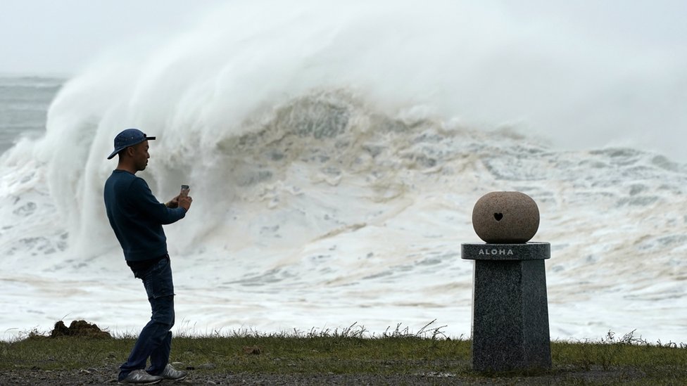 Un joven toma fotos de las altas olas generadas por el tifón Hagibis en la costa este de Japón. Un joven toma fotos de las altas olas generadas por el tifón Hagibis en la costa este de Japón.