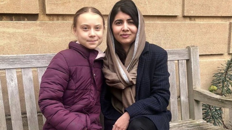 Greta e Malala posam para foto sentadas em banco