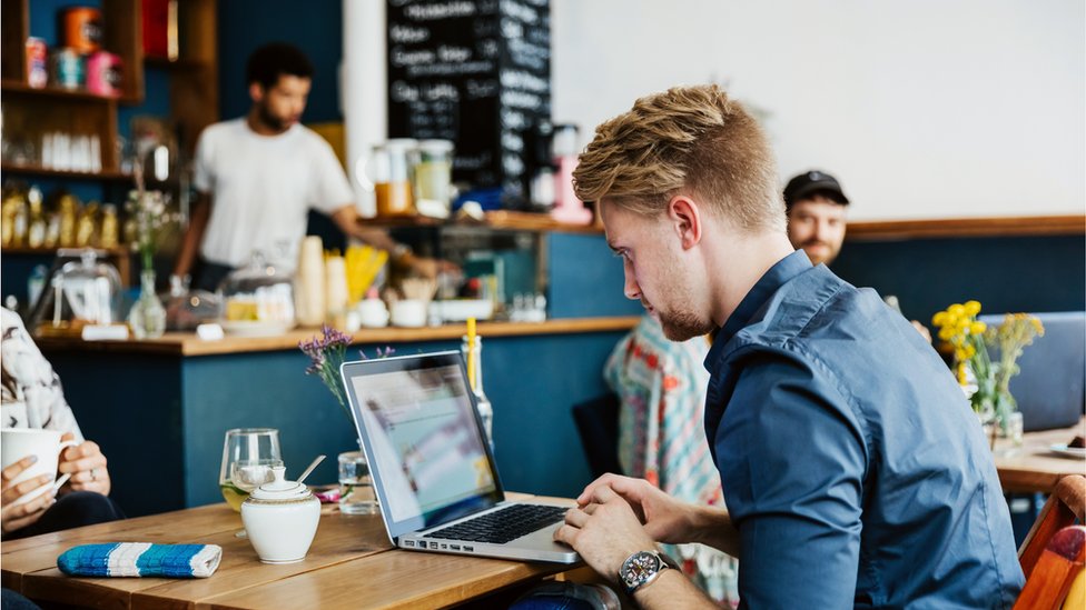 Un hombre frente a una laptop en un café