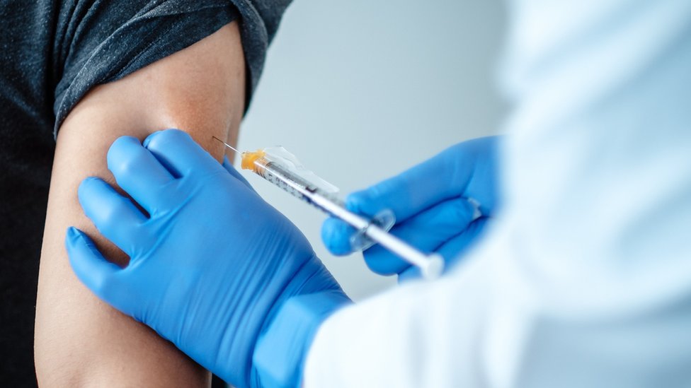 An undated handout picture made available by the German pharmaceutical company Biontec shows a person receiving a vaccine