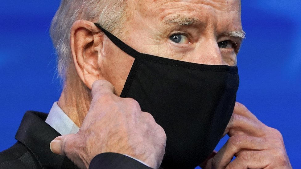 Joe Biden colocándose una mascarilla