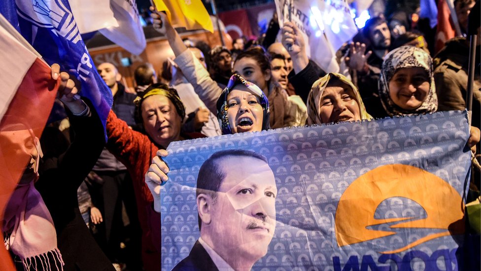 Сторонники Партии справедливости и развития Турции (AKP) машут партийными флагами и держат флаг с портретом президента Турции Реджепа Тайипа Эрдогана в Стамбуле