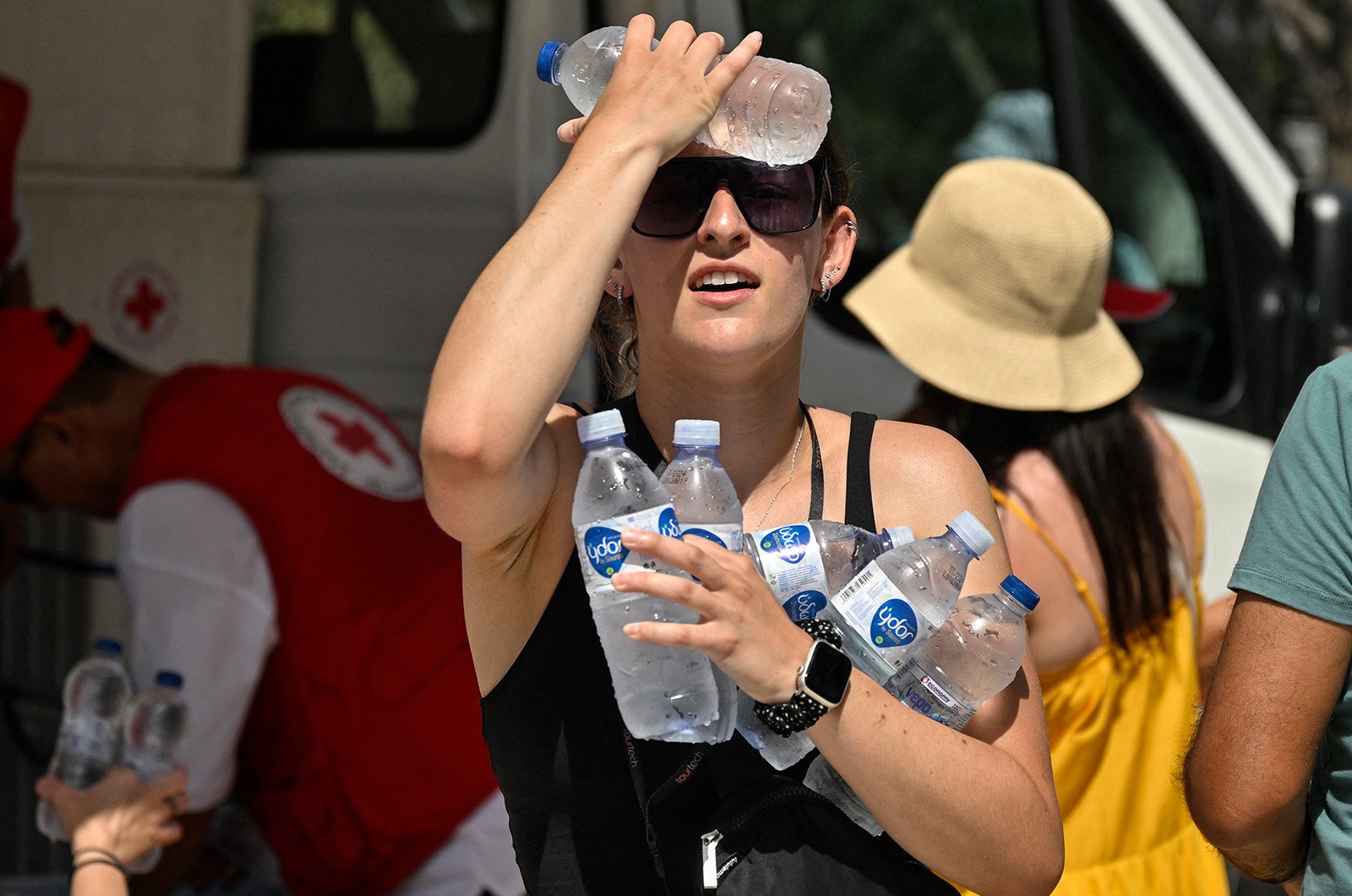 A woman cools off with cold bottles of water near the entrance of the Acropolis in Athens - July 20, 2023.