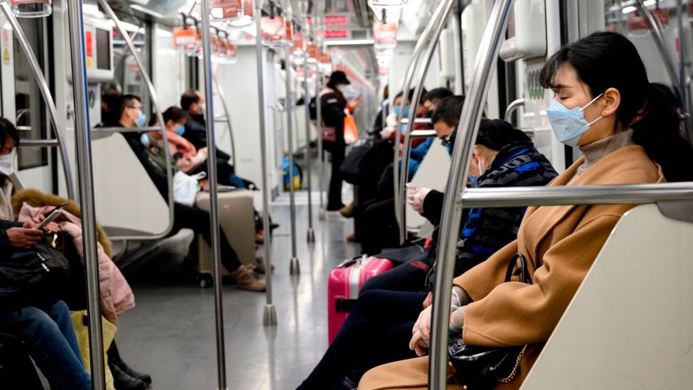 People wearing protective face masks commute on a train in Shanghai.