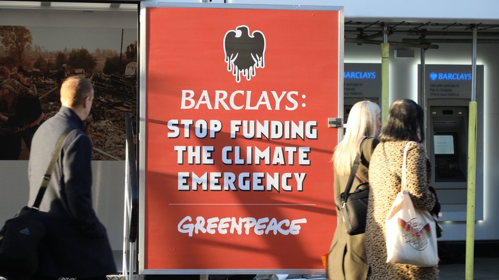 Люди проходят мимо митинга Гринпис в отделении Barclays