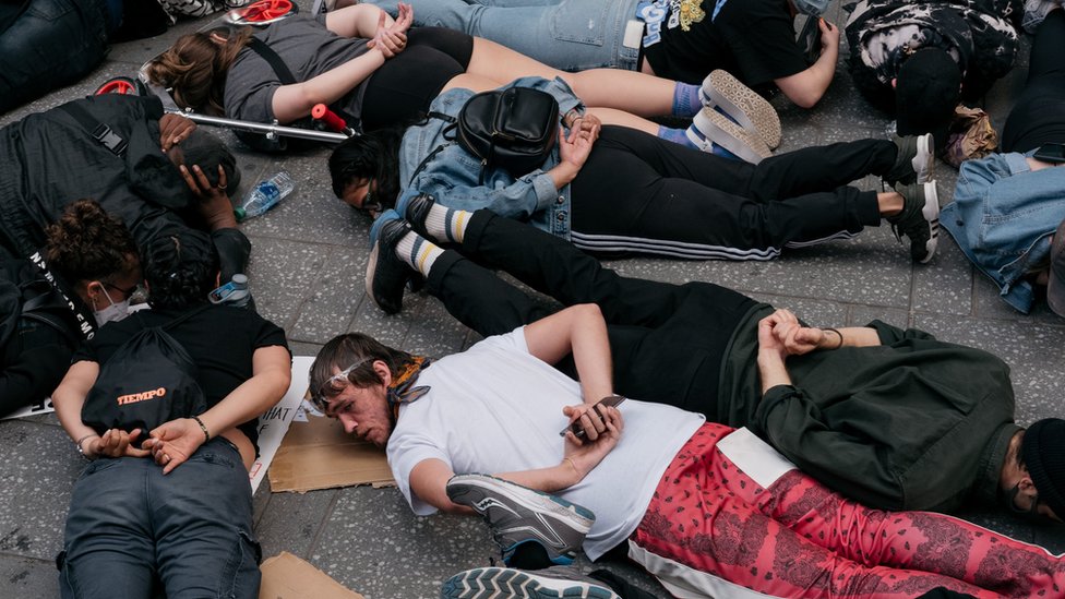 Протестующие лежат на земле, заложив руки за спину