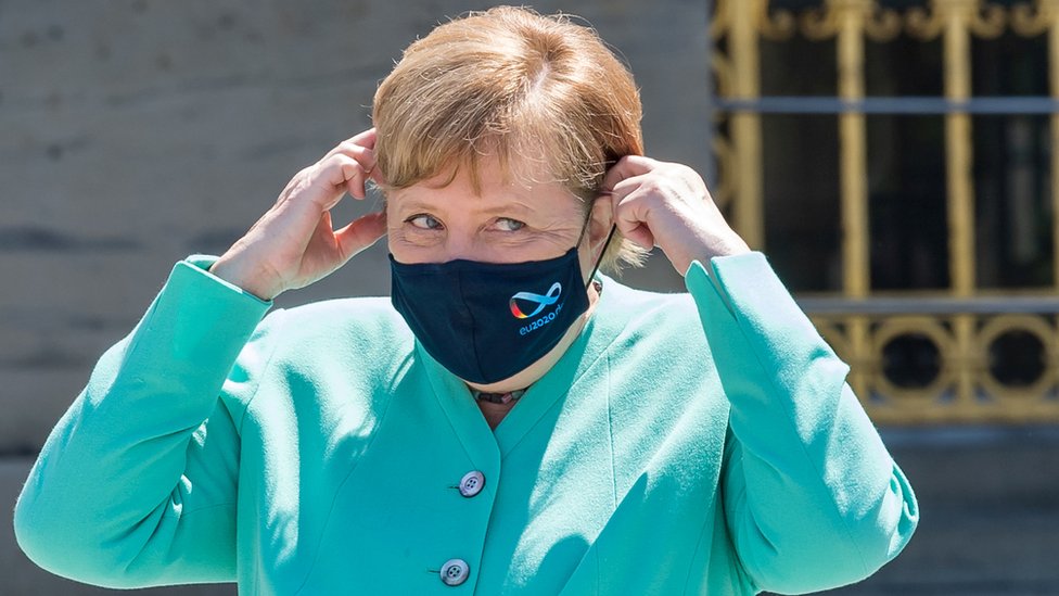 Канцлер Германии Ангела Меркель поправляет защитную маску по дороге на заседание кабинета министров Баварии на острове Херренкимзее, Германия, 14 июля 2020 г.