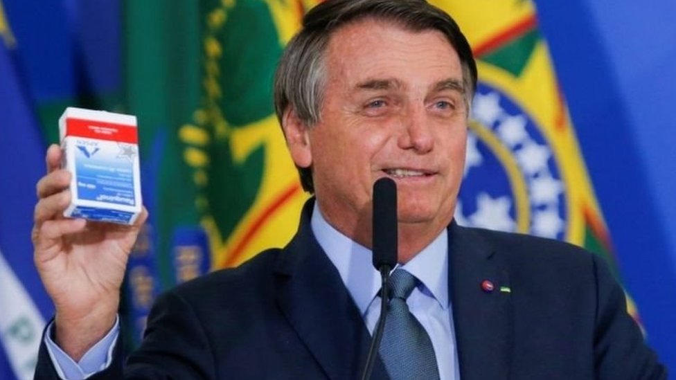 Jair Bolsonaro sorri e segura embalagem de hidroxicloroquina