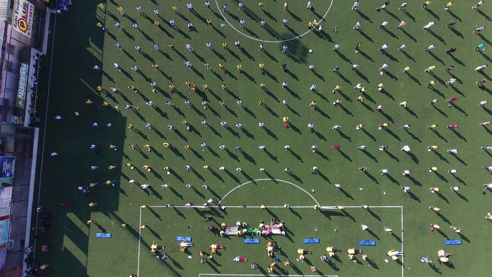 Vista aérea de campo de futebol em Paraisópolis, com dezenas de pessoas enfileiradas, mantendo o distanciamento social, durante formação de 'presidentes de rua' e brigadistas em Paraisópolis