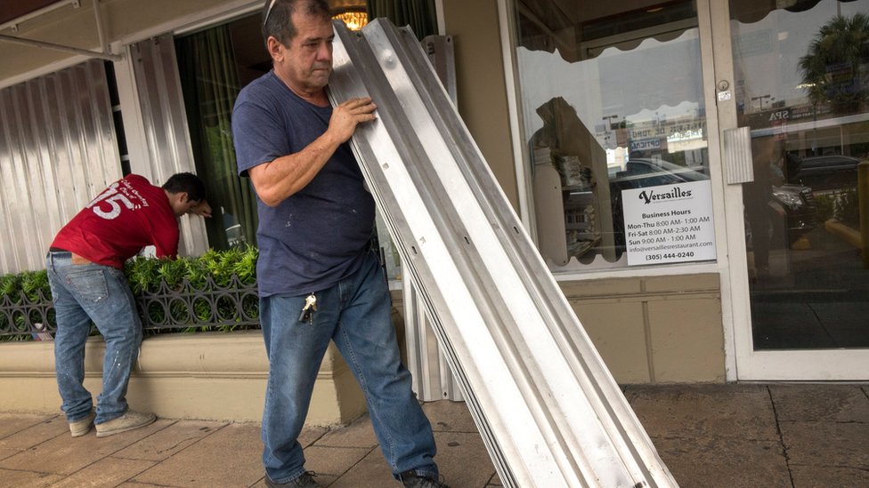 En el icónico Café Versalles, en el barrio de La Pequeña Habana, instalaron láminas metálicas para proteger las ventanas. Dos hombres ajustan láminas metálicas en las ventanas del icónico Café Versalles, en el barrio de La Pequeña Habana.