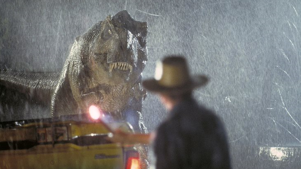 Scene from the 1993 movie Jurassic Park shows a T-Rex looking at a man