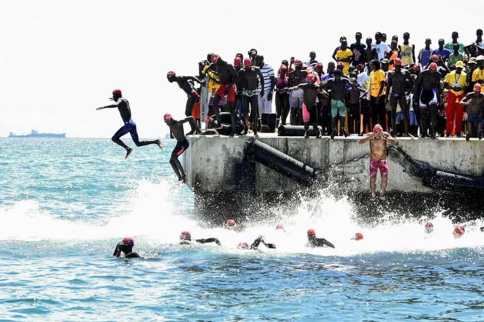 سباحون يقفزون من رصيف مقابل الشاطئ في داكار عاصمة السنغال، حيث يشاركون في سباق الأحد إلى جزيرة غوريه على بعد 2.5 كيلومتر