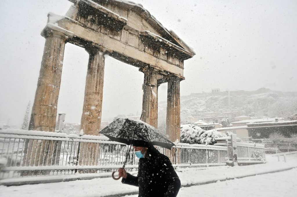 A man holding an umbrella in snow near the Roman Agora in central Athens