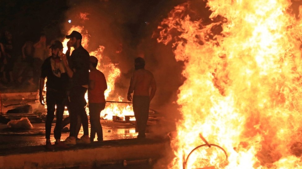 Иракские демонстранты сжигают предметы, чтобы заблокировать дорогу во время столкновений с силами безопасности